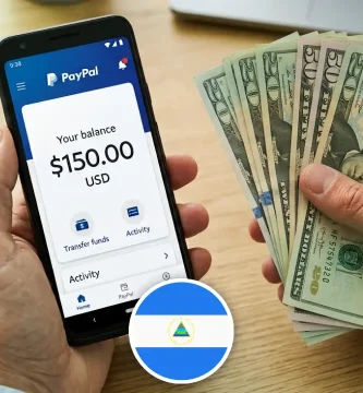 Mano sosteniendo celular con la app de PayPal y billetes en dólares, retiros en Nicaragua.